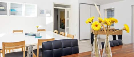 Un comedor con mesa de madera, sillas y un jarrón con flores amarillas.