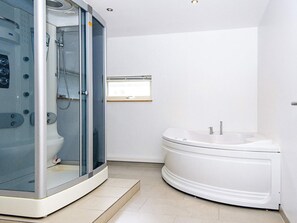 A modern bathroom with a glass-enclosed shower, a standalone bathtub, and a wall-mounted control panel. - 5 Star Holiday Home in Grenaa (Grenaa)