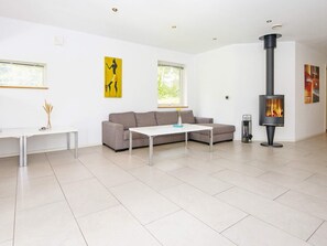 A modern living room with a sofa, a coffee table, a fireplace, and artwork on the walls. - 5 Star Holiday Home in Grenaa (Grenaa)
