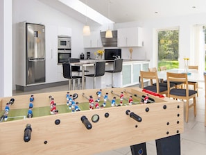Una cocina moderna con mesa de futbolín, electrodomésticos de acero inoxidable y un comedor con sillas y mesa.