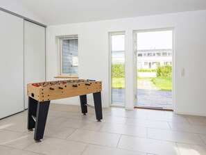 A room with a foosball table, a sliding glass door leading to a patio, and a window with blinds. - 5 Star Holiday Home in Grenaa (Grenaa)