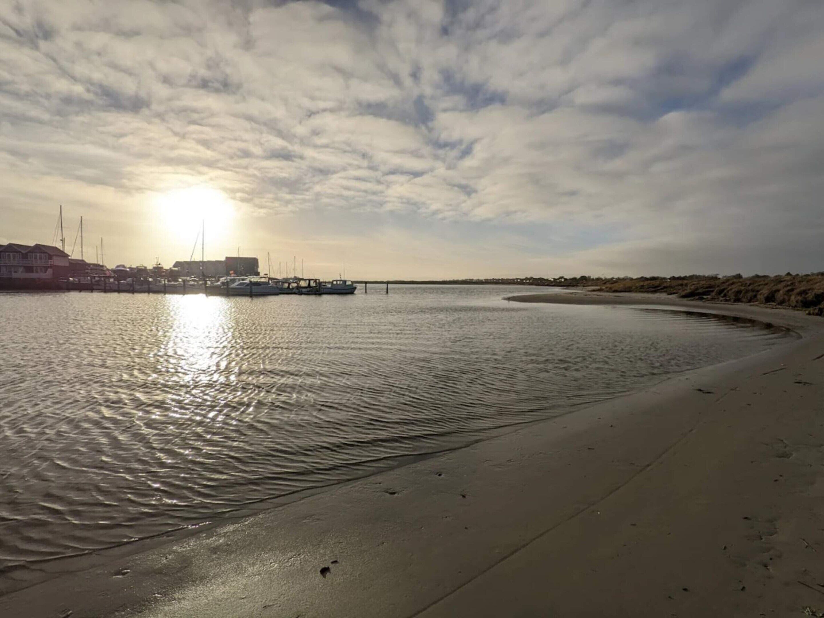 Un rivage paisible où sont amarrés des bateaux, une plage de sable et un ciel dégagé.
