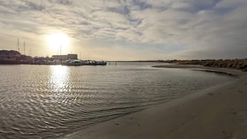 Un rivage paisible où sont amarrés des bateaux, une plage de sable et un ciel dégagé.