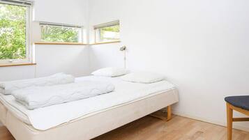A minimalist bedroom with a single bed, a bedside table, and a chair.
