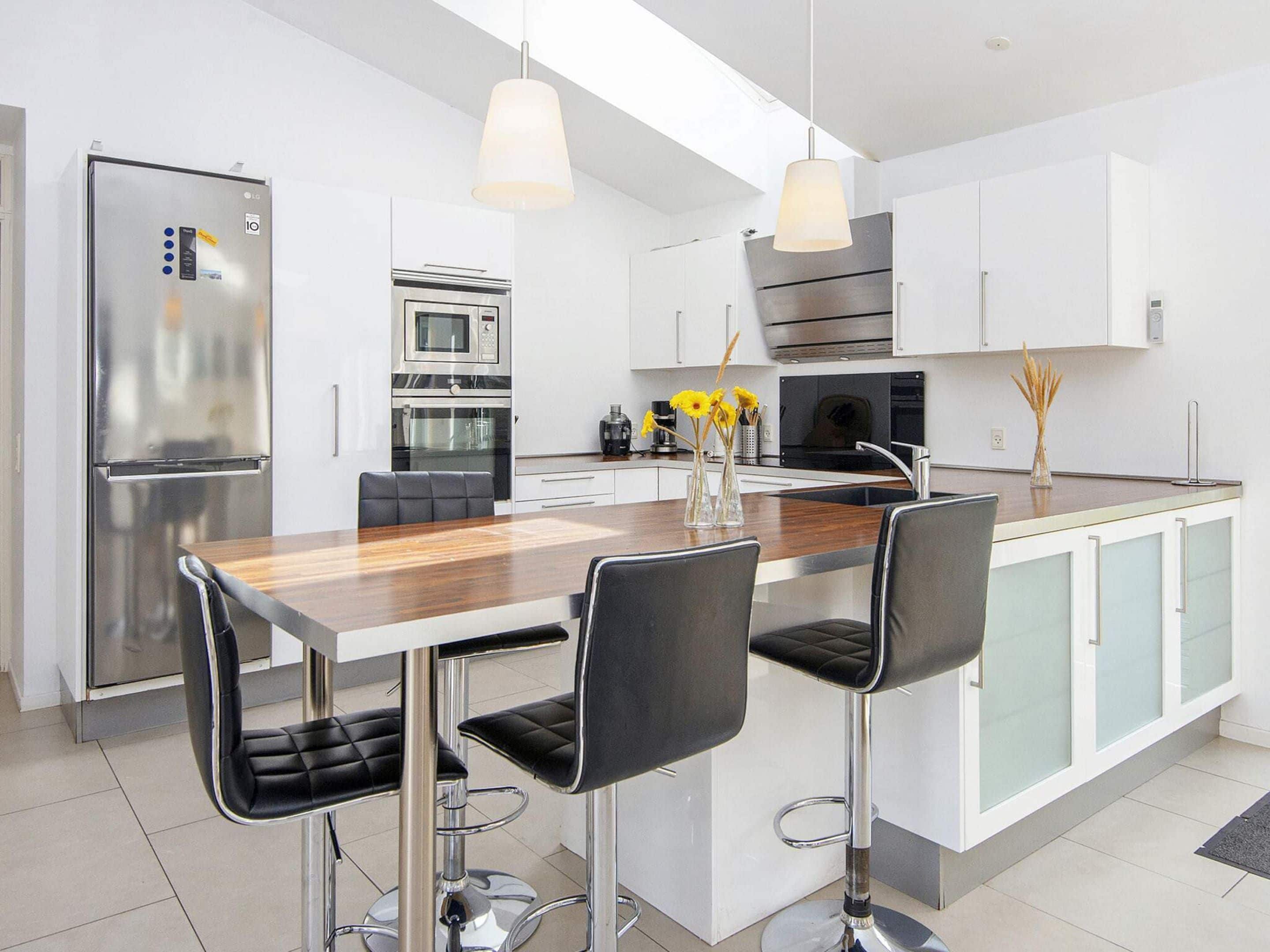 A modern kitchen with a central island, stainless steel appliances, and bar stools.