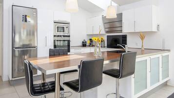 A modern kitchen with a central island, stainless steel appliances, and bar stools.
