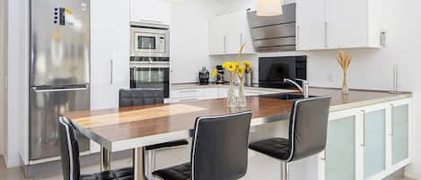 A modern kitchen with a central island, stainless steel appliances, and bar stools.