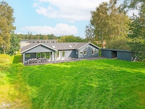 A residential property with a covered patio, a detached garage, and a well-maintained lawn. - 5 Star Holiday Home in Grenaa (Grenaa)