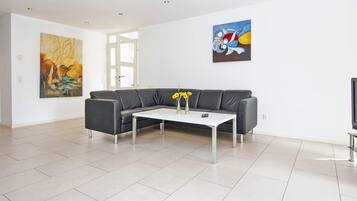 Una sala de estar moderna con un sofá gris, una mesa de centro blanca y dos cuadros en las paredes.