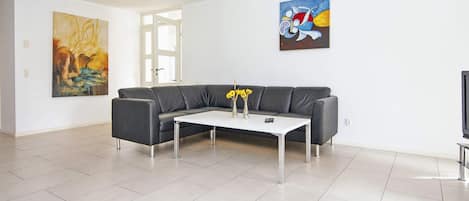 A modern living room with a grey sofa, a white coffee table, and two paintings on the walls.
