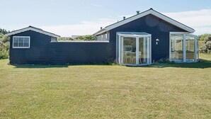 A modern house with a dark exterior, a large glass door, and a small attached garage. - 4 Person Holiday Home in Lokken (Lokken)