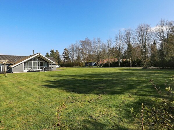 A residential property with a large lawn, a detached house with a patio, and a garage.