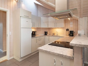A modern kitchen with white cabinetry, a glass backsplash, and a built-in stove.