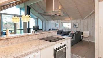 Een moderne keuken met granieten aanrecht, een ingebouwde oven en een zithoek met een bank en een stoel.