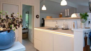 Une cuisine moderne avec des armoires blanches, un évier encastré et des luminaires suspendus.
