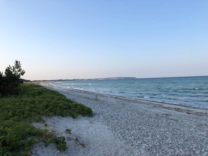 A pebbled beach with a clear sky and distant land. - 4 Person Holiday Home in Ebeltoft-by Traum (Ebeltoft)