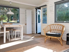 Une pièce comprenant une table à manger, des chaises, un fauteuil en osier, une fenêtre et une porte.