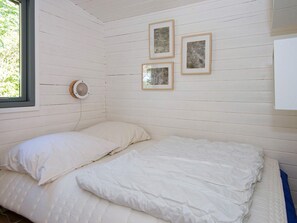 A room with a bed, a window, and three framed pictures on the wall.