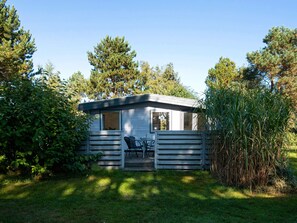 A small cabin with a deck, surrounded by trees and vegetation. - 4 Person Holiday Home in Ebeltoft-by Traum (Ebeltoft)