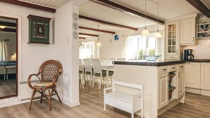 Una cucina con mobili bianchi, un tavolo da pranzo in legno e un'isola centrale.
