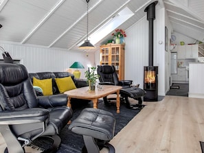 A modern living room with leather furniture, a wooden coffee table, a fireplace, and a kitchen area.
