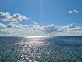A calm sea under a clear sky with scattered clouds.