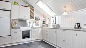 A modern kitchen with white cabinetry, a built-in oven, a microwave, and a coffee maker.