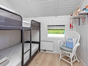 A bunk bed room with a window, a wicker chair, and a radiator. - 4 Star Holiday Home in Vaeggerlose (Vaeggerlose)