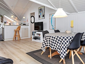 A modern living space with a dining area, kitchen, and entertainment setup. - 4 Star Holiday Home in Vaeggerlose (Vaeggerlose)