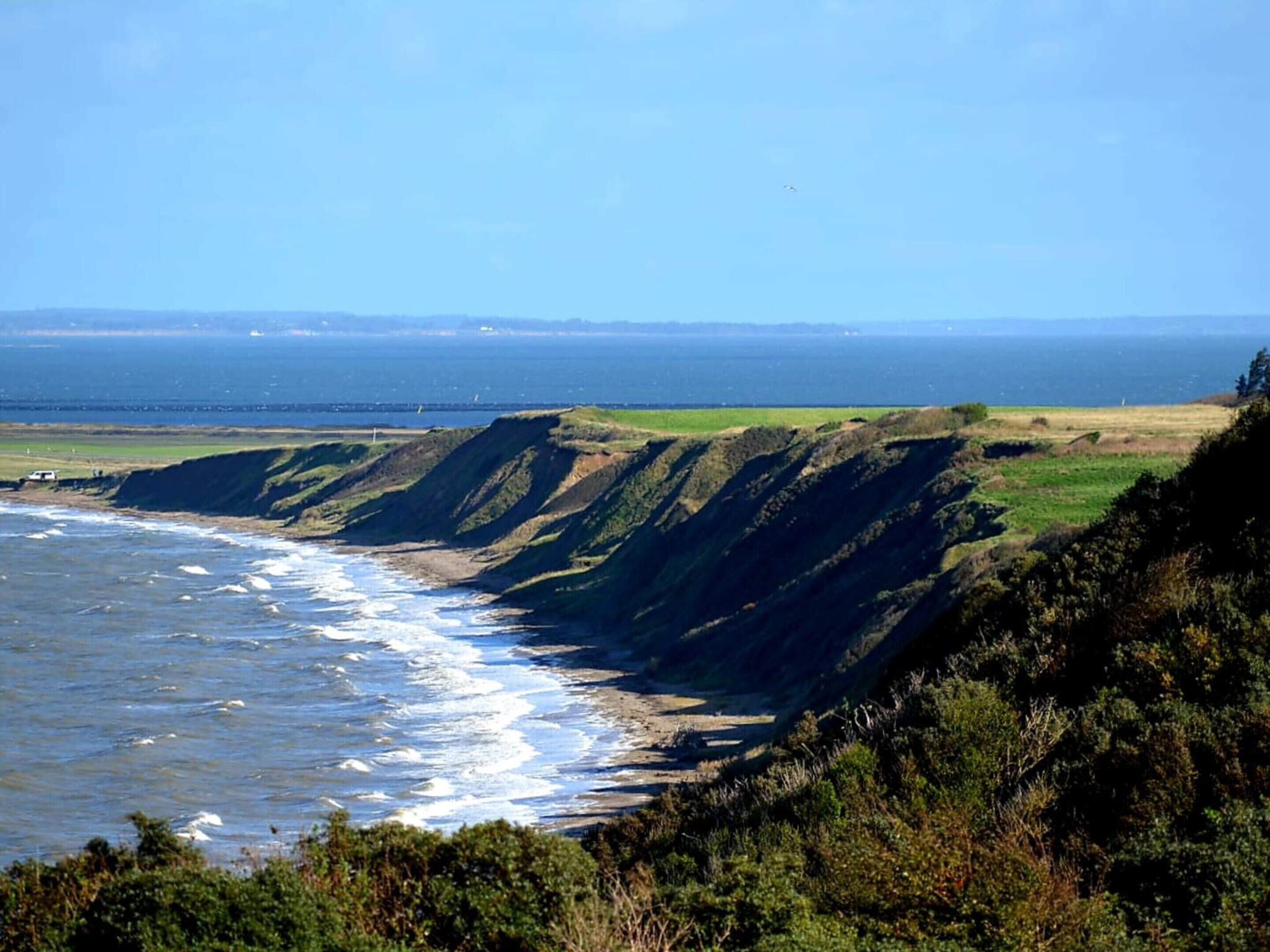 Un paysage côtier avec des falaises, une plage et l’océan.