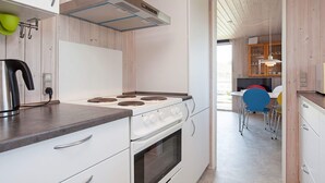 A modern kitchen with a stove, oven, and a view into the dining area. - 4 Star Holiday Home in Struer (Struer)