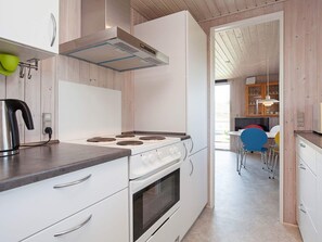A modern kitchen with a stove, oven, and a view into the dining area. - 4 Star Holiday Home in Struer (Struer)