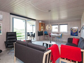 Un intérieur moderne comprenant un canapé, des fauteuils, une table à manger et un téléviseur.
