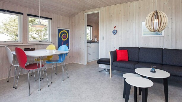 A modern interior with a dining area, sofa, and a kitchen visible through an open doorway. - 4 Star Holiday Home in Struer (Struer)