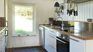 A compact kitchen with a built-in dishwasher, a sink, and a stove. There is a window providing natural light and a view of greenery outside. - Spacious Holiday Home in Oksbol near Sea (Oksbol)