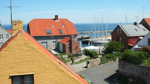 A coastal town with red-roofed buildings, a marina with boats, and a clear view of the sea. - 4 Person Holiday Home in Allinge (Allinge)