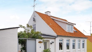 A two-story building with a red-tiled roof, white walls, and a grey lower section. - 4 Person Holiday Home in Allinge (Allinge)