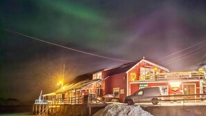 A brightly lit building with a sign reading "matkroken" at night, featuring a dock and a snow-covered ground. - 4 Person Holiday Home in Rebbenes (Tromsø)