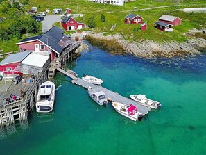 Ett flygbildsbild av ett kustområde med en brygga, båtar och röda byggnader.