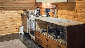 A kitchen with wooden walls, a stove, cabinets, and a sink. - 4 Person Holiday Home in Rebbenes (Tromsø)