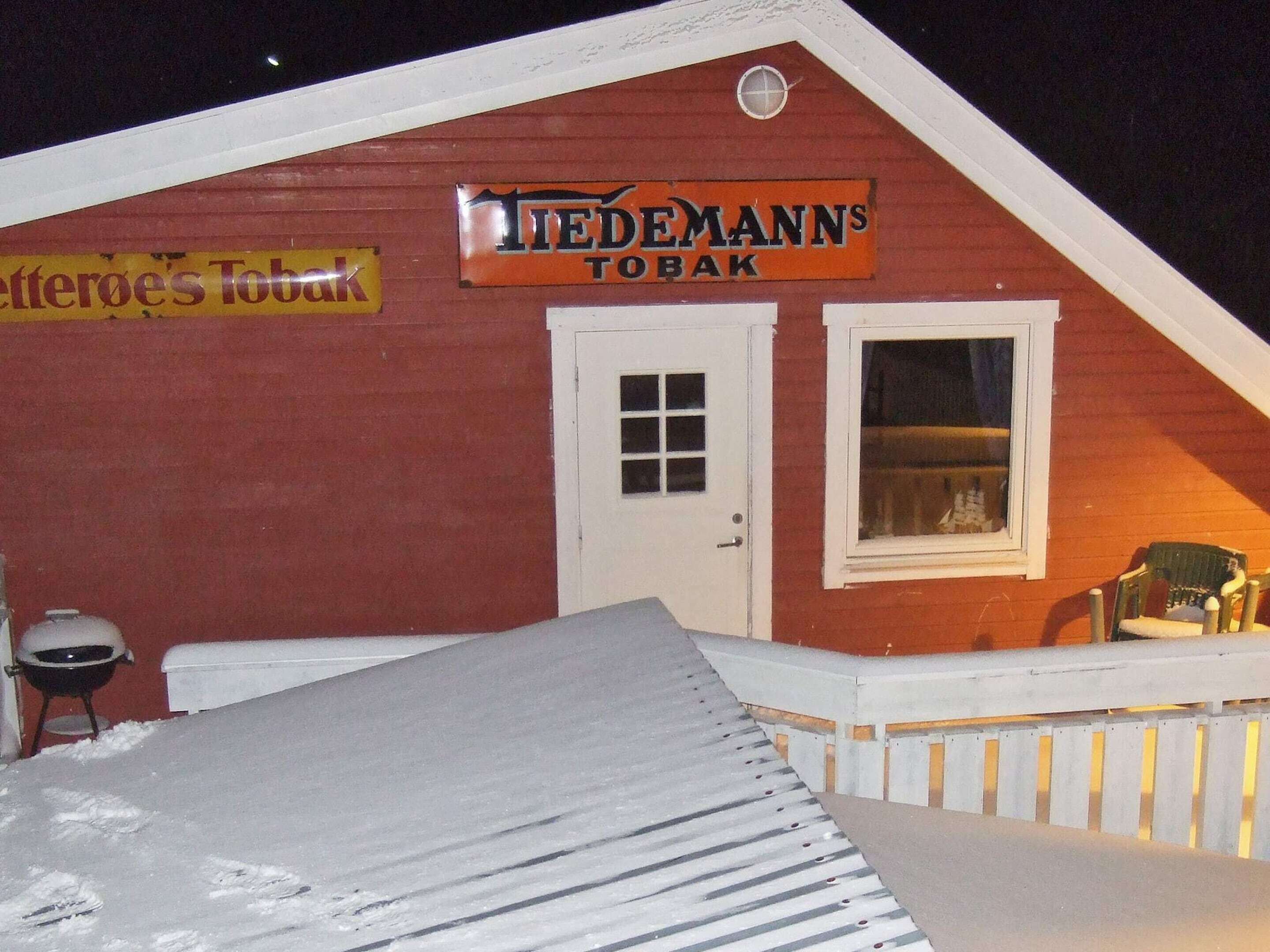 Un bâtiment rouge avec une enseigne indiquant « Tiedemann's Tobak » et une porte blanche.