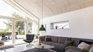 A modern living room with a sectional sofa, a round coffee table, and a large window providing a view of the outdoors. - 6 Person Holiday Home in Otterup-by Traum (Otterup)