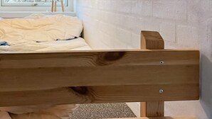 A bed with a wooden headboard, a window with a view of trees, and a brick wall. - 6 Person Holiday Home in Otterup-by Traum (Otterup)