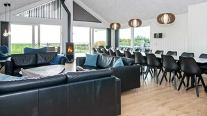 A modern lounge area with leather sofas, black chairs, and a fireplace. - 5 Star Holiday Home in Ebeltoft (Ebeltoft)