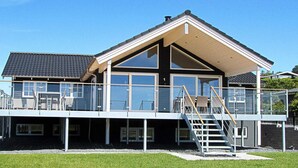 A modern house with a large balcony, a staircase, and a clear blue sky. - 5 Star Holiday Home in Ebeltoft (Ebeltoft)