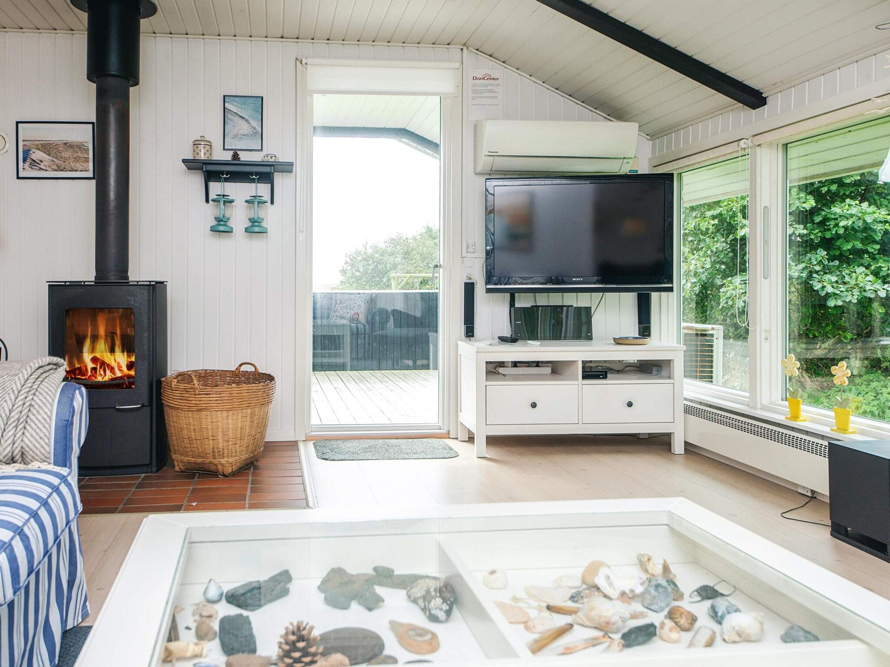Una sala de estar acogedora con chimenea, un televisor de pantalla plana y una mesa de vidrio con piedras decorativas.