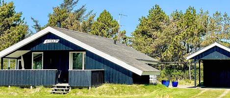 Une cabane bleue avec une pancarte indiquant « GIVAS » et une table de pique-nique à l’extérieur.