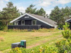 A modern cabin with a sloped roof, a visible chimney, and a sign that reads 'GIVAS'.