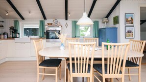 A spacious kitchen with a central island, wooden chairs with cushioned seats, and a hanging pendant light.