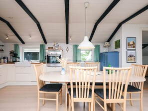 A spacious kitchen with a central island, wooden chairs with cushioned seats, and a hanging pendant light.